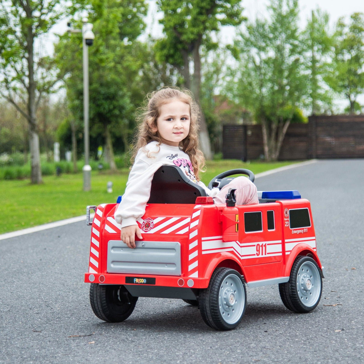 12V Kids Fire Truck Ride-On – Red children's electric car with emergency lights, megaphone, fire shovel, and sprinkler, designed for kids aged 3-8. Back view with kid sitting inside.