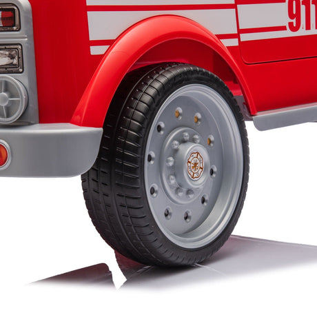 12V Kids Fire Truck Ride-On – Red children's electric car with emergency lights, megaphone, fire shovel, and sprinkler, designed for kids aged 3-8. View of the wheels.
